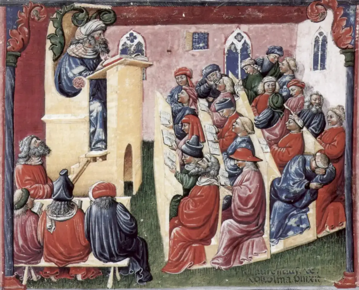Miniatura medievale a colori: un maestro in cattedra legge un libro mentre gli studenti seduti sui banchi seguono sui propri testi, alcuni chiacchierano e uno in fondo dorme